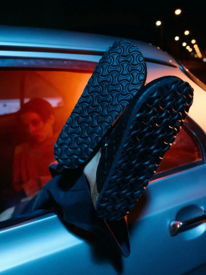 A sleek smooth black leather clog featuring a deeply embossed bone pattern across the entire upper.