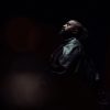 A moody and cinematic portrait of Kanye West performing under heavy stadium lights during a live listening event for his album Bully.