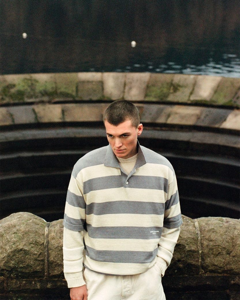 A model wearing a garment dyed sailing jacket from Stone Island Marina's SS26 collection, photographed at a working marina.